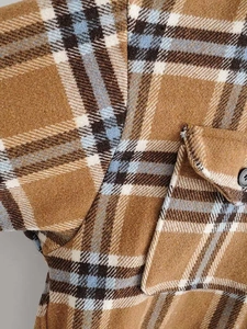 Detailed macro view of the brown plaid flannel texture with pocket and button detail