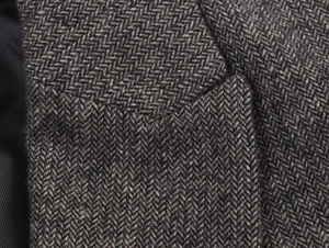 Macro view of herringbone texture on brown wool blazer with refined stitching details
