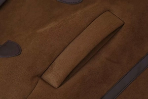 Macro detail of brown faux suede jacket with leather piping on slanted pocket seam