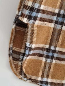 Detail of curved hem and side slit on thick plaid flannel shirt jacket in brown and blue