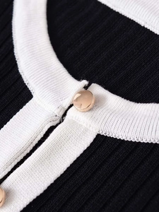 Gros plan sur les boutons dorés et la maille côtelée du cardigan noir et blanc chic