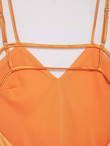 Détail d'une robe midi en satin orange vif avec décolleté en V et bretelles décoratives