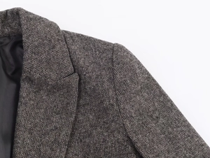 Close-up detail of grey herringbone wool fabric and black silk lining on a blazer