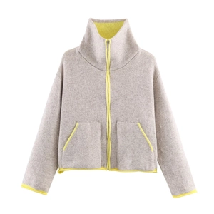 Detail of grey knitted jacket showing neon yellow fleece lining and silver metal zipper