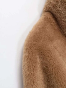 Gros plan d'une veste en fausse fourrure marron montrant la texture douce et la couture
