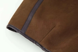 Detail view of brown suede jacket showing precise dark leather trim and premium stitching