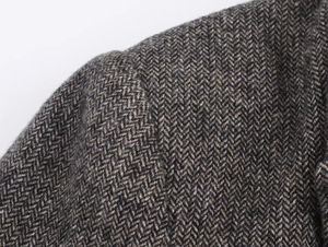 Macro shot of herringbone wool blend fabric on classic tailored blazer shoulder