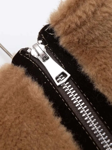 Détail de la veste en velours noir avec col en fausse fourrure marron et zip en métal argenté