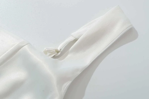Detail des verstellbaren Trägers und des weißen Satinstoffs mit seidigem Glanz am Sommerkleid