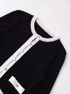 Gros plan détaillé des boutons dorés et de la maille sur ce cardigan noir et blanc