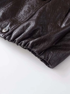 Detail of vintage textured leather jacket featuring an elastic hem and dark round button