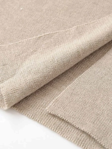 Gros plan sur la maille fine beige montrant les détails des plis doux du vêtement