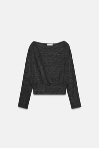 Detail of dark grey off-shoulder knit top featuring ribbed texture and fitted waist hem
