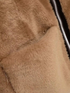 Gros plan sur la texture pelucheuse camel et la fermeture éclair noire de la veste d'hiver