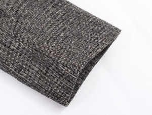 Detailed close-up showing the herringbone texture and cuff stitching of a grey blazer jacket