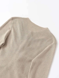 Détail du haut en tricot beige clair montrant la texture douce et le col rond ajusté