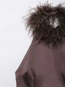 Détail du haut dos nu en satin marron avec bordure en plumes et fermeture à bouton au cou
