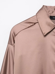 Detailed close-up of dark pink satin shirt featuring smooth silk texture and lapel design