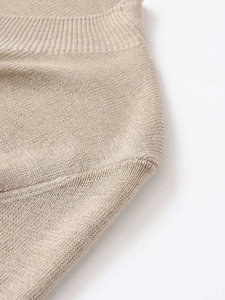 Détail du tissu en maille beige montrant la texture côtelée et les coutures de l'épaule