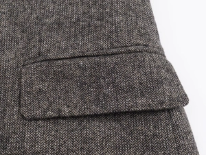 Close-up of herringbone pattern and stitching on the pocket of a gray blazer