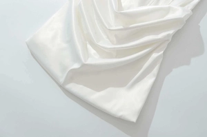 Detailed close-up of premium white satin dress featuring elegant draped pleats and silky texture