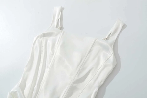 Close-up of white satin corset dress featuring square neck straps and structured seams