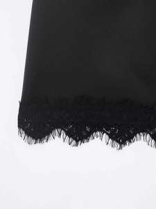 Detail eines schwarzen Satinstoffs mit feiner Wimpernspitze und floralem Saumdesign