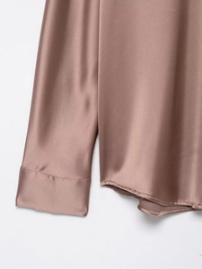 Detail of rose gold satin shirt featuring smooth stitching and curved hemline