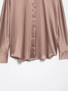 Detail of silk satin shirt fabric showing premium luster and champagne pink buttons