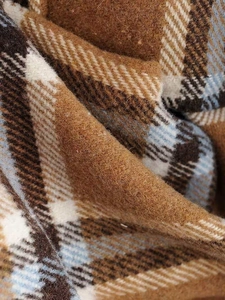 Detailed macro view of the thick checkered wool fabric with soft brushed plaid texture