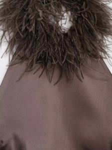 Détail de la robe en satin marron café avec une encolure ornée de plumes d'autruche douces
