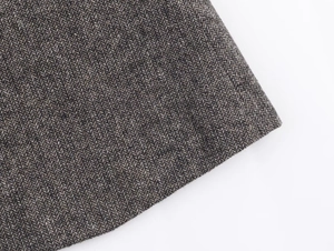 Macro shot of herringbone weave fabric detail on a brown wool blend blazer coat