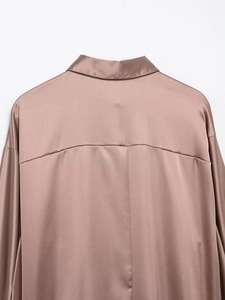 Detailed close-up of smooth satin fabric texture and dropped shoulder seam on the shirt