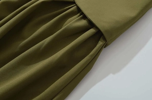 Detail of army green pleated fabric with fine woven texture and structured waistline folds
