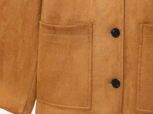 Dettaglio macro della giacca scamosciata color cammello con grandi tasche e bottoni neri