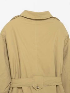Dettaglio del retro del trench color kaki con spalline, cintura in vita e bottone ambra
