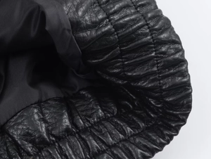 Detail of elastic gathered cuff on a black faux leather jacket with lychee texture