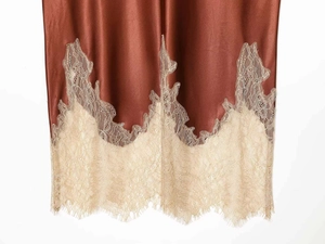 Detailed close-up of lace hemline on a cinnamon brown satin skirt with eyelash trim