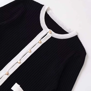 Cardigan en tricot noir pour femme avec bordure blanche et boutons dorés style chic épuré