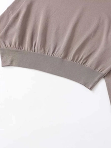 Detailed close-up of ribbed hem and fine knit texture on a dusty pink knitted top