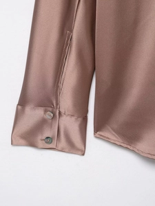 Detail of mocha satin shirt sleeve with silk texture and glossy shell buttons