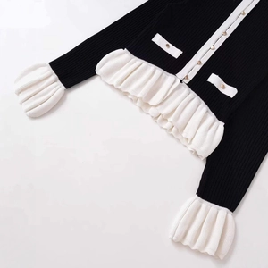 Cardigan en maille noir ajusté avec volants blancs et boutons dorés élégants