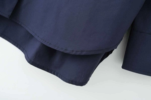 Detail view of navy blue cotton poplin shirt showing curved hem and precise stitching