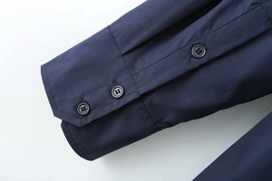 Detail of dark blue cotton poplin shirt cuff with three resin buttons and neat stitching