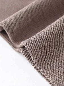 Close-up of warm brown fine ribbed knit fabric with smooth hem and texture details