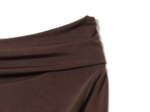 Detailed close-up of dark brown gathered pleats and waistline texture on the long dress