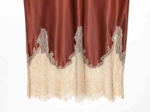 Detailed close-up of brown satin skirt hem with delicate beige eyelash lace trim