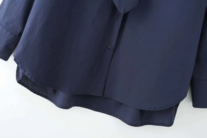 Detail of dark blue poplin shirt featuring front buttons and curved overlap hemline