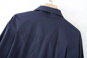 Close-up of navy cotton poplin shirt back with yoke and box pleat detail on a hanger