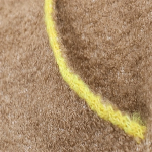 Detail of brown faux fur texture with contrasting bright yellow knit trim on a jacket